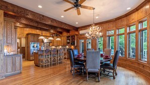 A spacious kitchen with wooden cabinets, a central island, and a dining area with a chandelier. - Amitola at Yonahlossee (Boone)