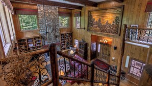 A multi-level wooden interior with a fireplace, bookshelves, and a staircase. - Amitola at Yonahlossee (Boone)