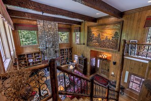 Ein mehrgeschossiges Interieur aus Holz mit Kamin, Bücherregalen und einer Treppe.
