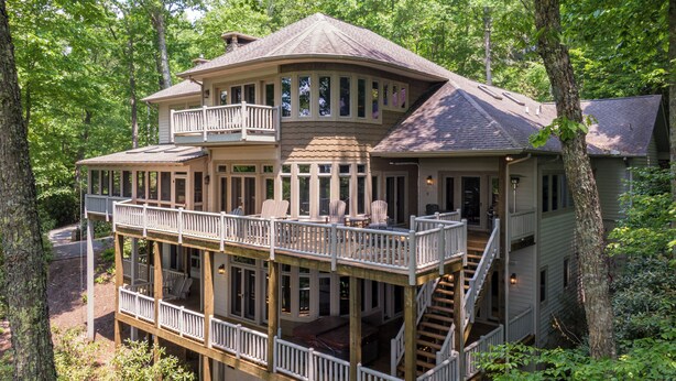 A two-story wooden house with a balcony, multiple windows, and a staircase leading to the upper level. - Amitola at Yonahlossee (Boone)