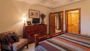 A bedroom with a bed, a wooden dresser, a chair, a television, and a ceiling fan. - Caribou Crossing at The Lodges at Elkmont (Banner Elk)