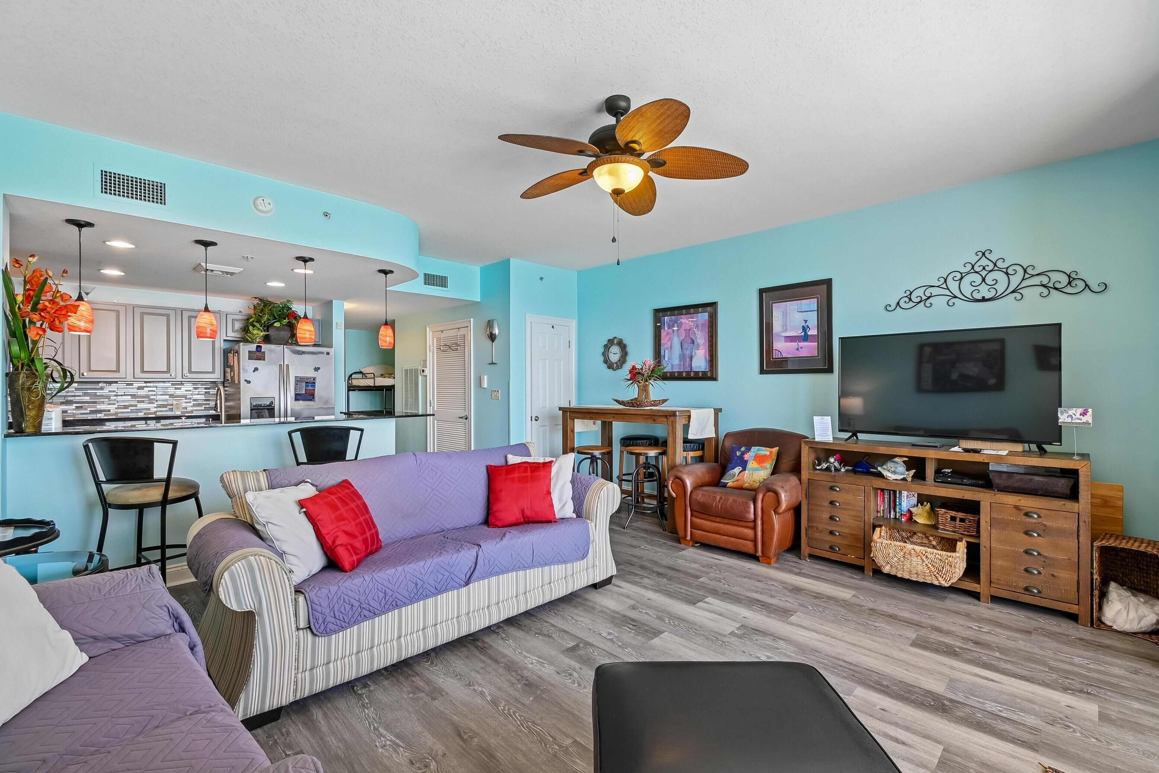 A living room with a sofa, chairs, a TV, and a dining area with a table and chairs.