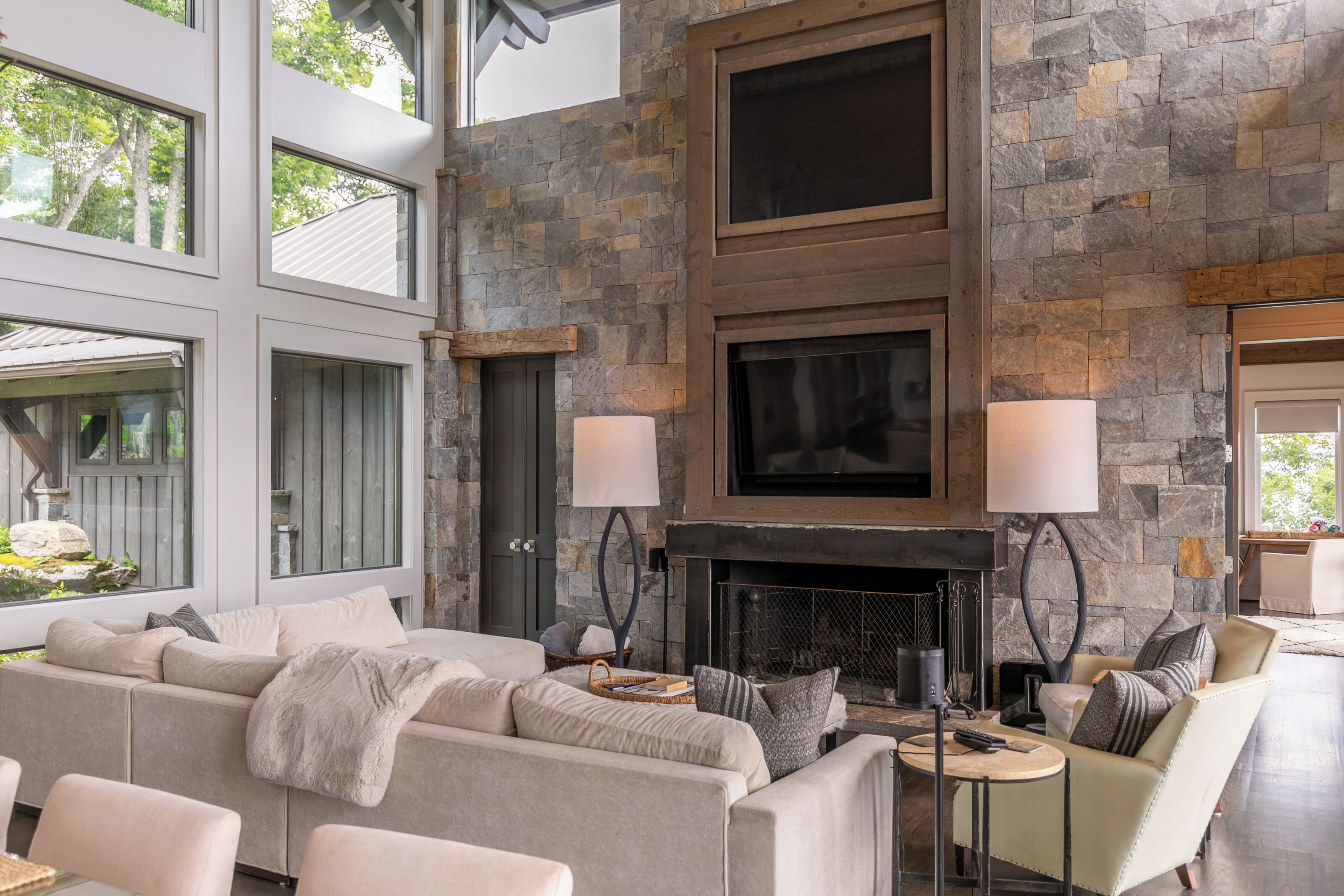 A spacious living area with a stone fireplace, large windows, and comfortable seating.