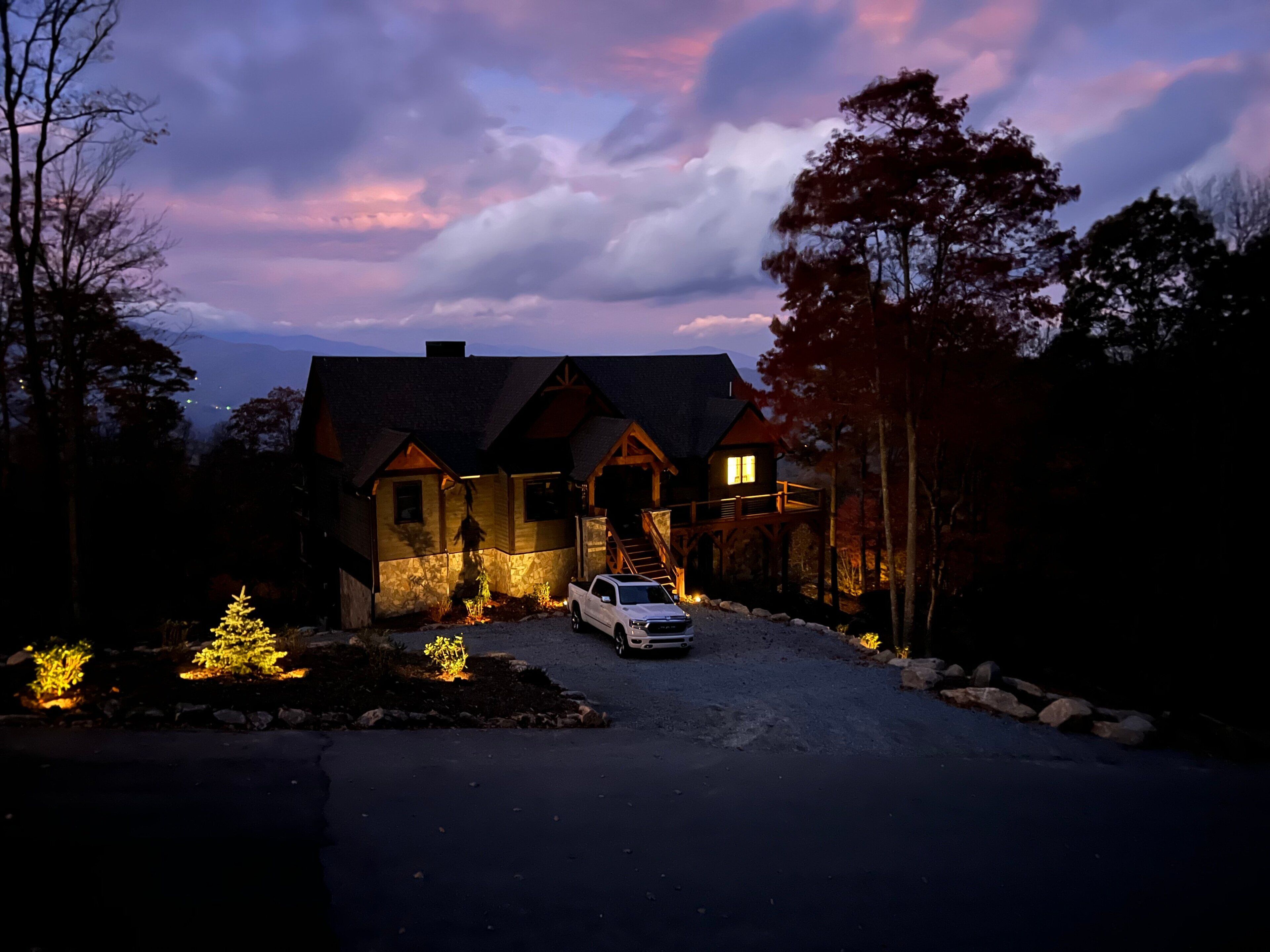 A large, rustic house with a driveway and a car parked in front.