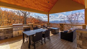 An outdoor deck with a grill, seating, and a view of autumn trees and mountains. - On the Rocks (Banner Elk)