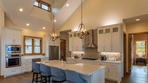 A spacious kitchen with a large island, bar stools, and modern appliances. - On the Rocks (Banner Elk)