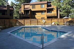 A rectangular pool with a wooden deck and a lifeguard chair.