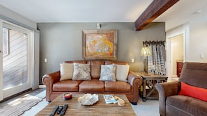 A living room with a brown leather sofa, a coffee table, and a painting on the wall.