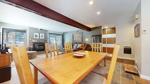 A dining area with a wooden table, chairs, and a fireplace.