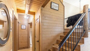 Puisesti sisustettu tila, jossa on portaikko, peili ja seinillä olevia kehystettyjä tauluja.