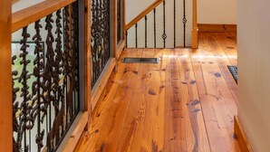 A wooden staircase with a handrail, a window with blinds, and a ceiling light fixture. - Skyline Escape Stunning Long Range Views, Hot Tub, Firepit, Lawn Games (Lenoir)