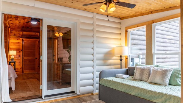 A cozy room with a bed, a sliding glass door leading to a bathroom, and a ceiling fan. - Skyline Escape Stunning Long Range Views, Hot Tub, Firepit, Lawn Games (Lenoir)