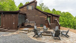 A rustic log cabin with a stone patio and Adirondack chairs. - Skyline Escape Stunning Long Range Views, Hot Tub, Firepit, Lawn Games (Lenoir)