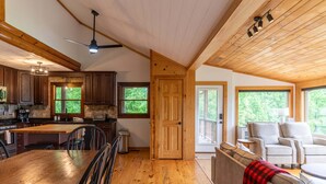 A spacious kitchen with wooden cabinets, a dining table, and a ceiling fan. - Skyline Escape Stunning Long Range Views, Hot Tub, Firepit, Lawn Games (Lenoir)