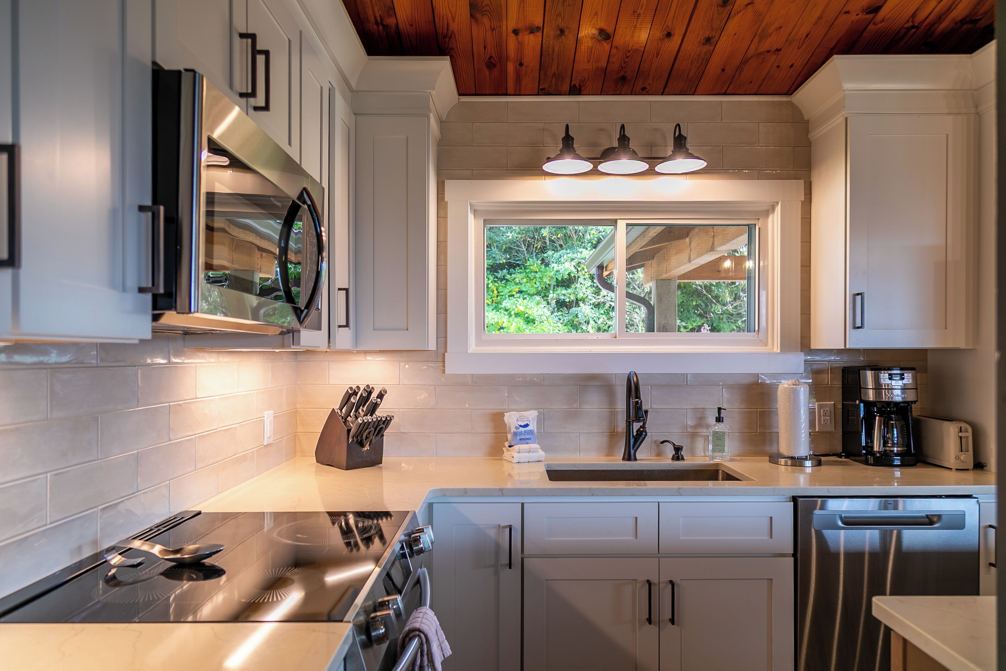 Una cocina moderna con electrodomésticos de acero inoxidable, un ventanal con vistas y un techo de madera.