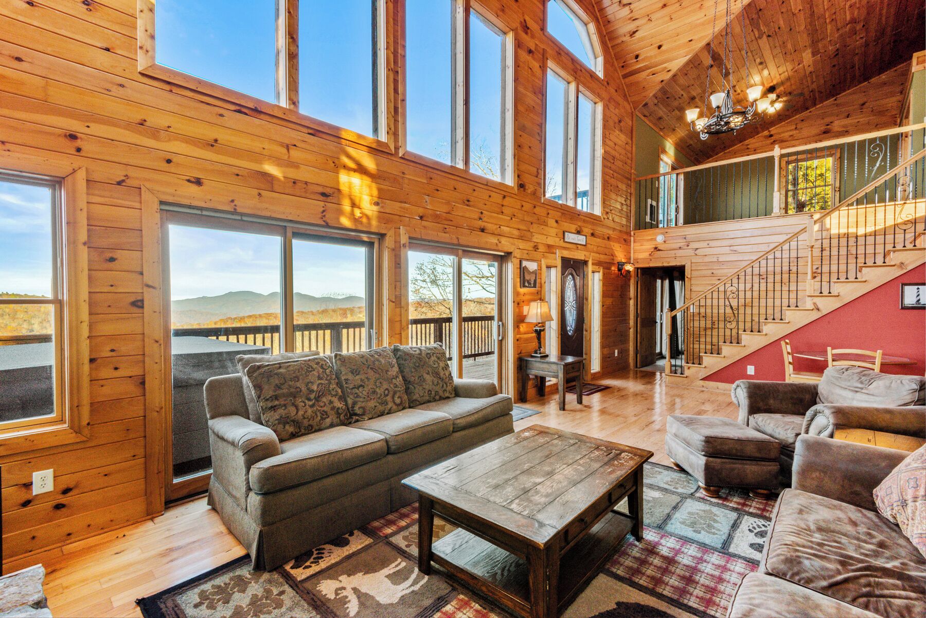 A spacious living room with a large sofa, a coffee table, and a view of the mountains through large windows.