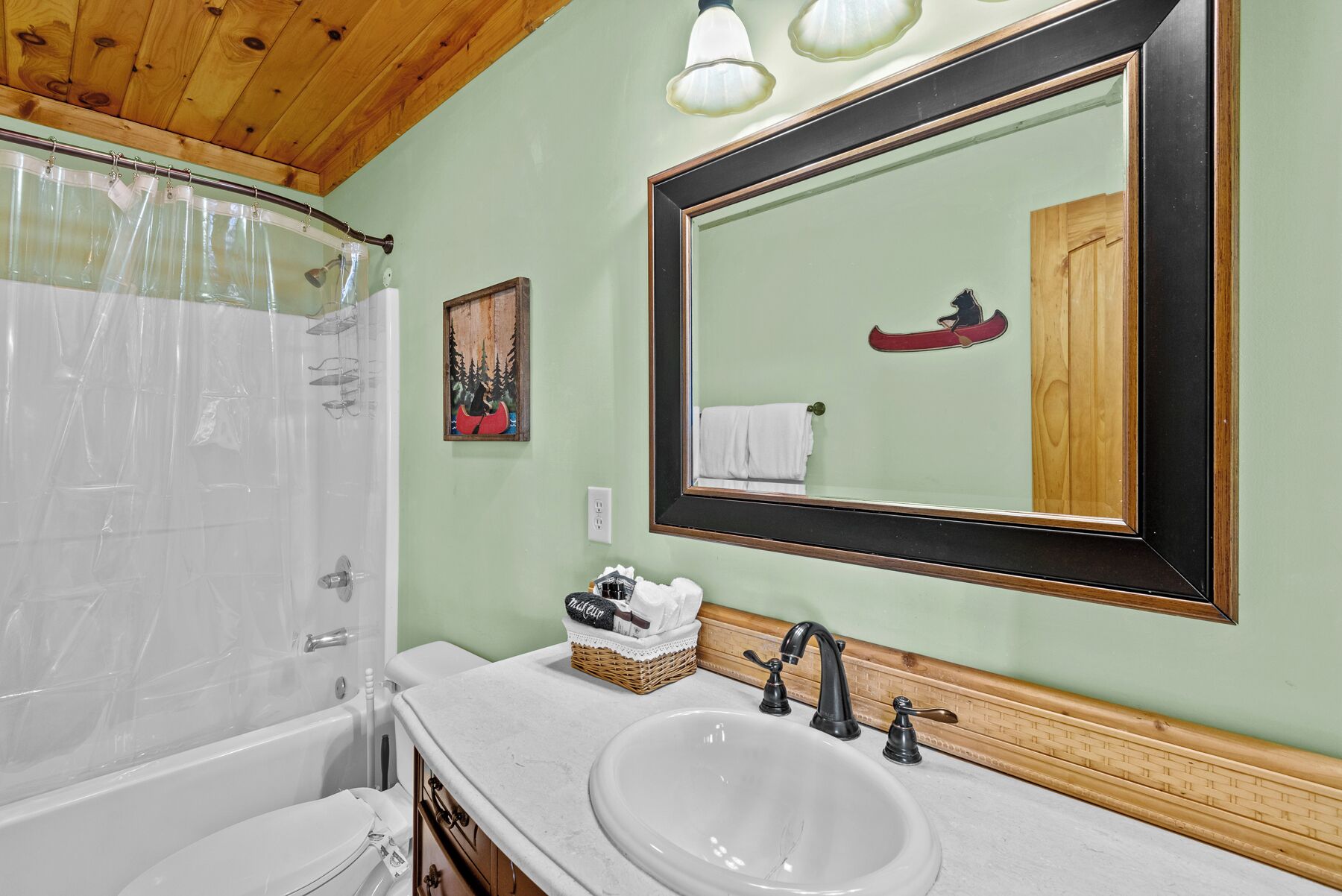 A bathroom with a bathtub, a large mirror, a sink, and a shower curtain.