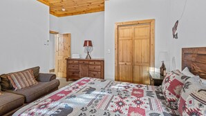 A bedroom with a wooden ceiling, a bed with a patterned bedspread, a wooden dresser, a wooden wardrobe, and a wooden bench. - Beech Mountain Breeze - Views, pet Friendly, hot Tub, Sleeps 14 (Banner Elk)