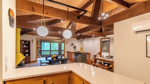 A kitchen with wooden beams, a white countertop, and a dining area with a view. - Blue Ridge Retreat at Linville Land Harbor (Newland)