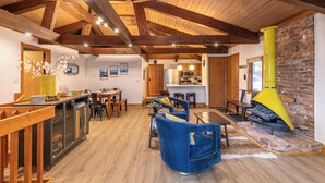A spacious living area with wooden beams, a fireplace, and a kitchen in the background. - Blue Ridge Retreat at Linville Land Harbor (Newland)