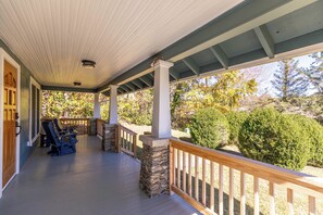 A covered porch with stone pillars, wooden railings, and outdoor seating. - Stella Maris - own Blowing Rock Pet Friendly Updated Craftsman Bungalow (Blowing Rock)
