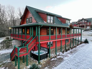 Eine Blockhütte mit Veranda, Whirlpool und einer Treppe, die zum Eingang führt.