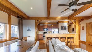 A spacious living area with a wooden ceiling, a dining table, a sofa, and a kitchen in the background. - Endless Grandfather View at Echota (Boone)