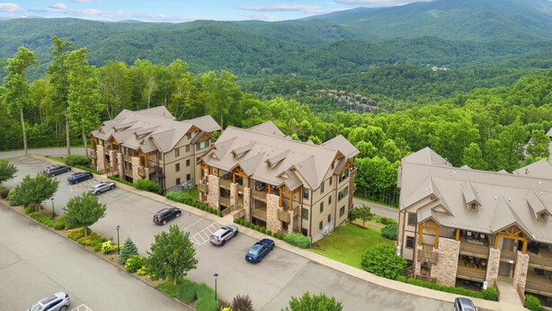 A multi-story hotel with a stone facade, multiple balconies, and a parking lot. - Endless Grandfather View at Echota (Boone)