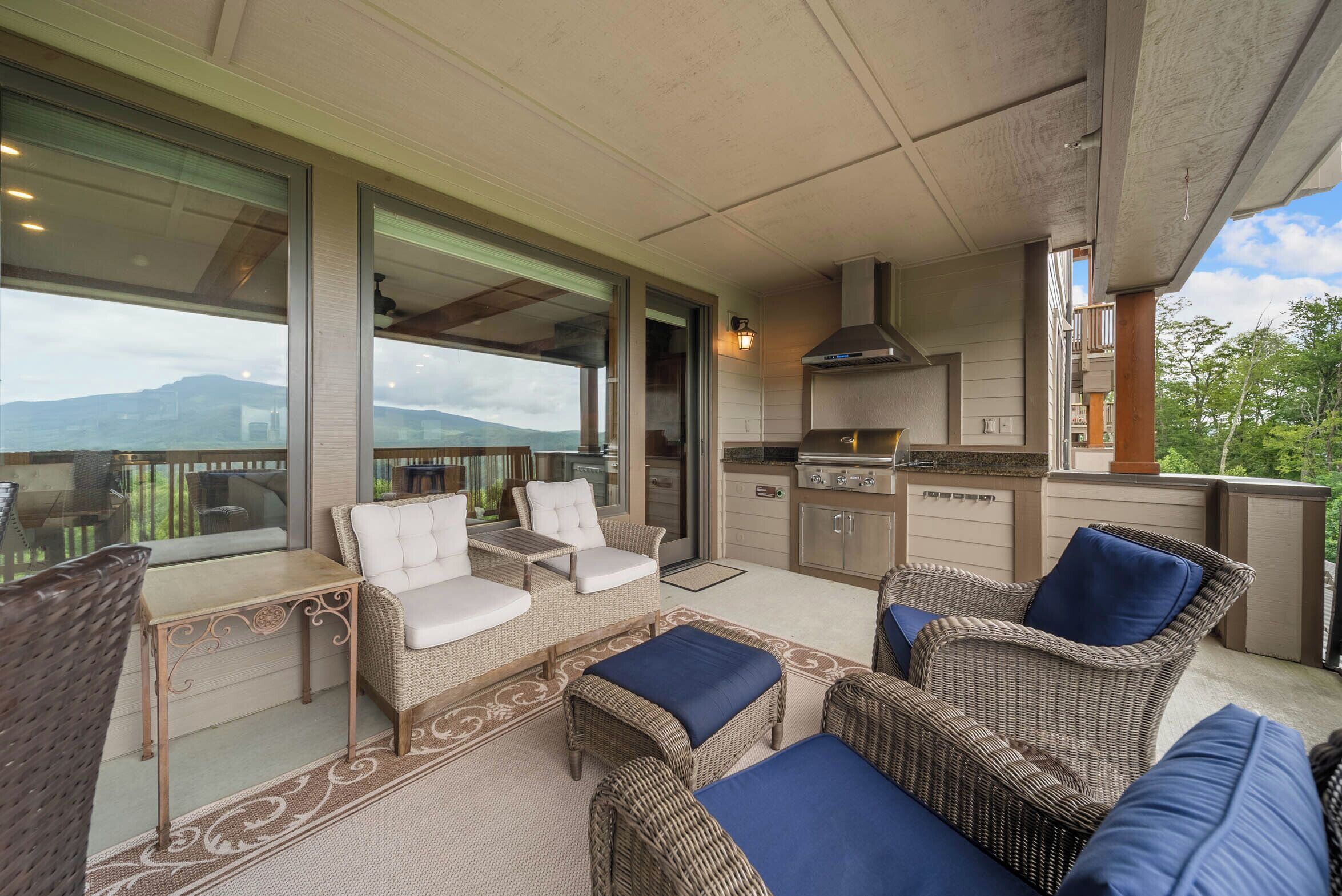 A covered outdoor seating area with wicker furniture and a view of mountains.