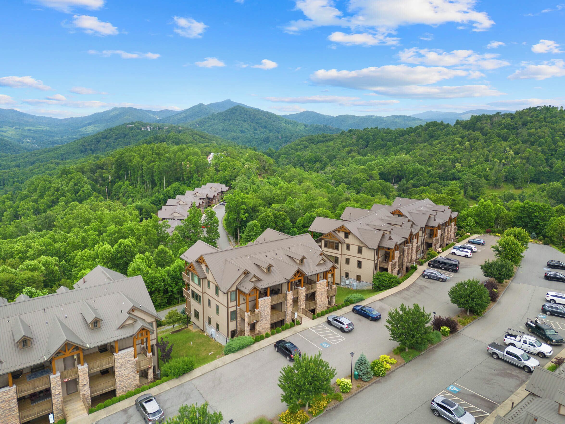 A multi-story hotel with a central courtyard, surrounded by lush greenery and mountains in the background.