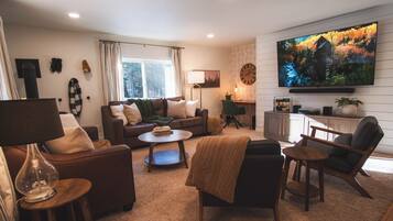 Un salon comprenant un canapé, un fauteuil, une table basse et un téléviseur fixé au mur.