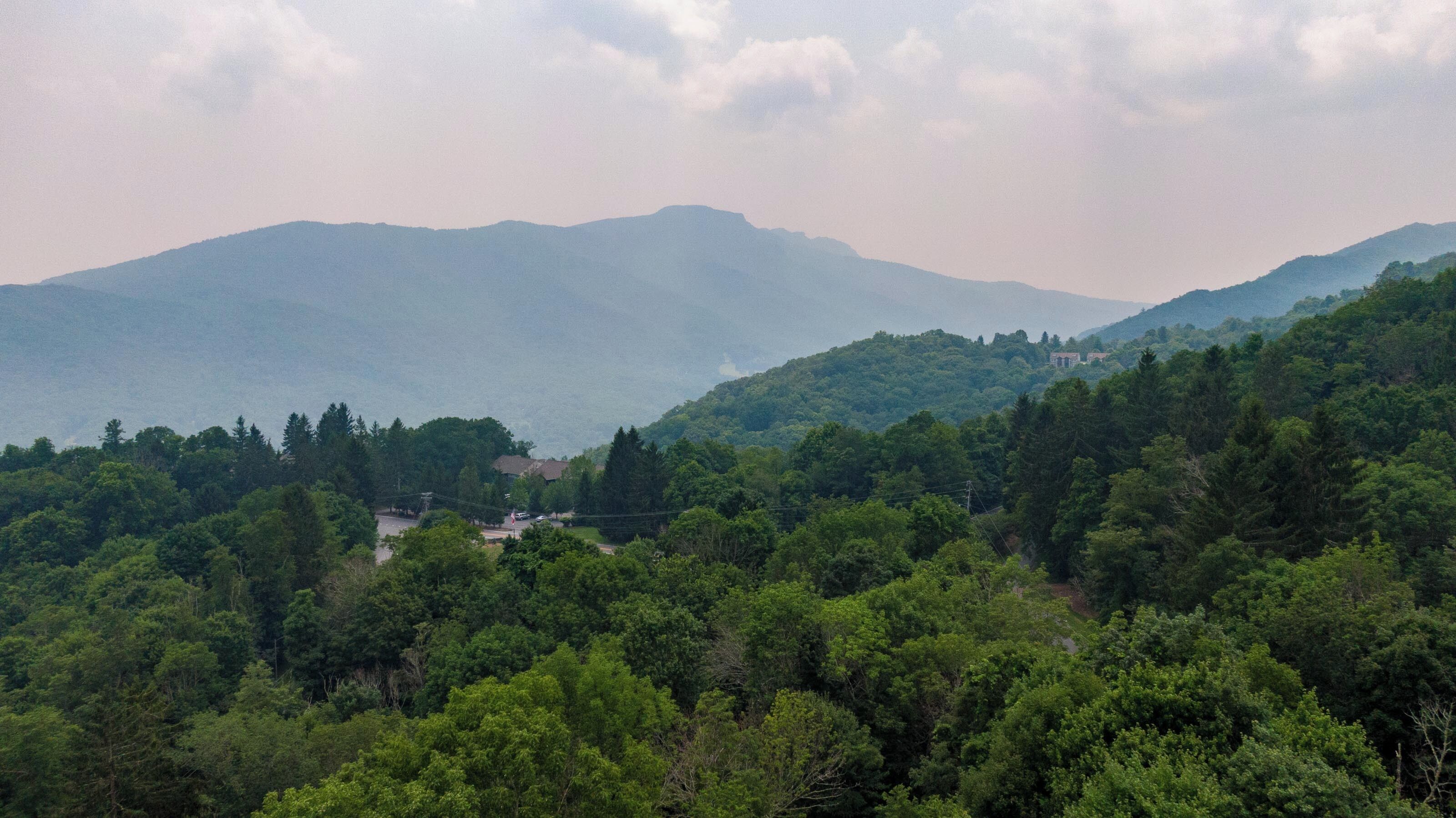 Un paisaje montañoso con un bosque denso y algunos edificios en el valle.
