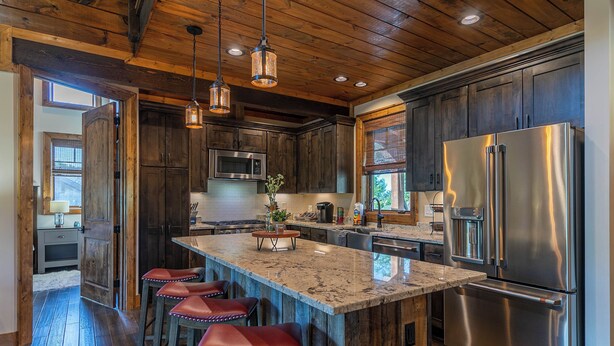 A kitchen with a large island, stainless steel appliances, wooden cabinets, and bar stools. - Happy Camper at Eagles Nest (Banner Elk)