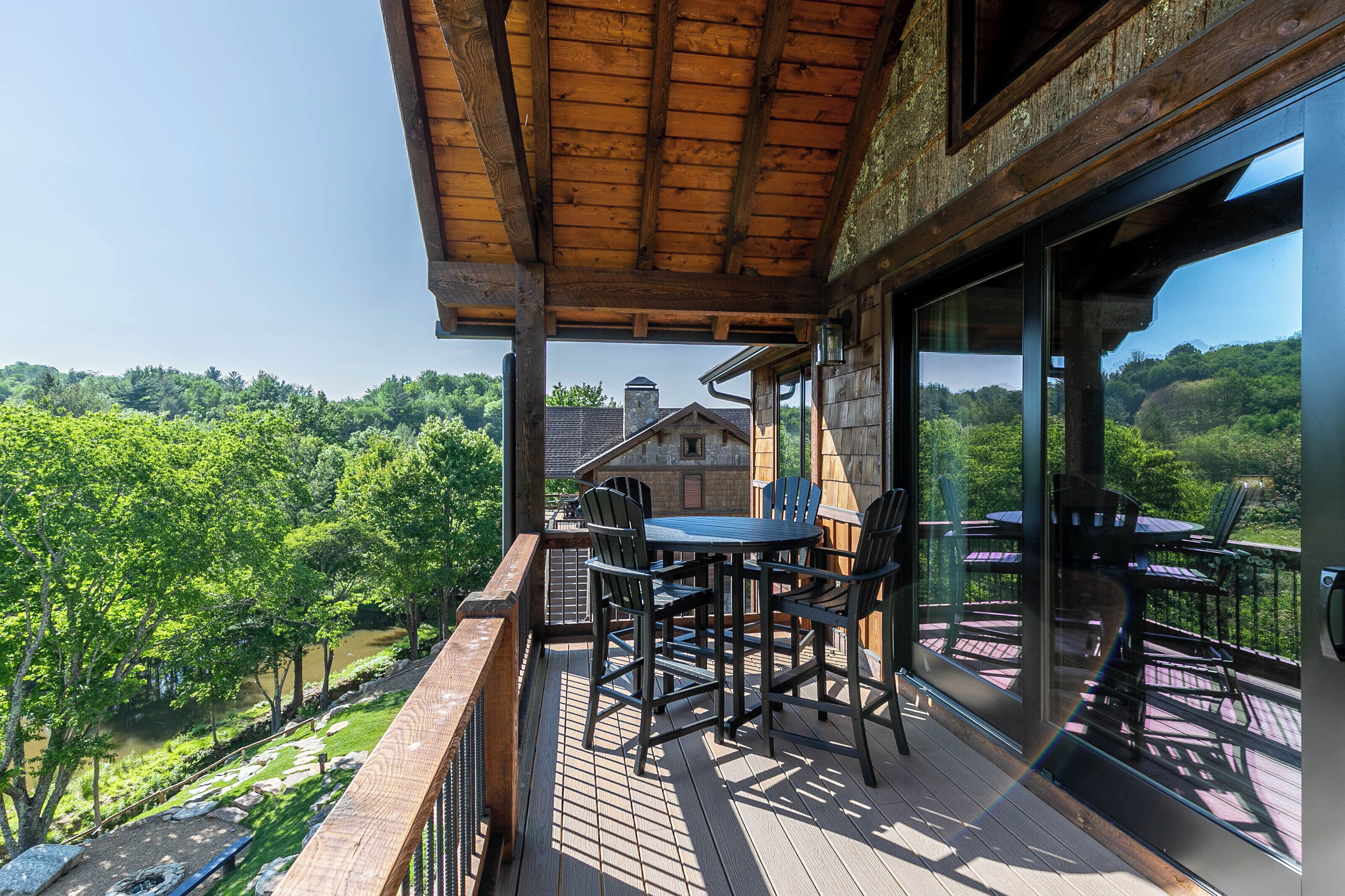 A wooden deck with a table and chairs, overlooking a lush green landscape.