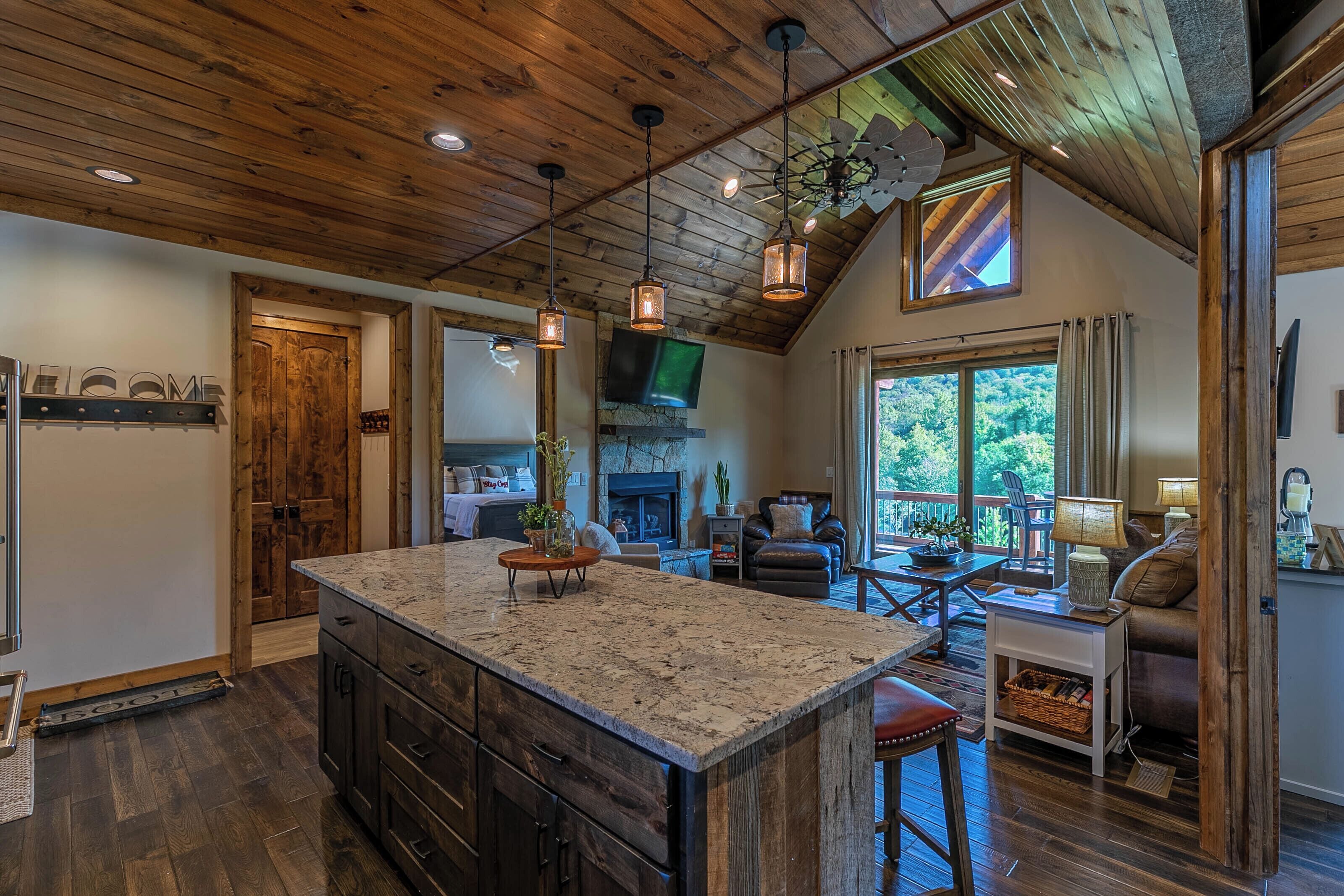 A spacious kitchen with a large island, wooden ceiling, and pendant lighting.