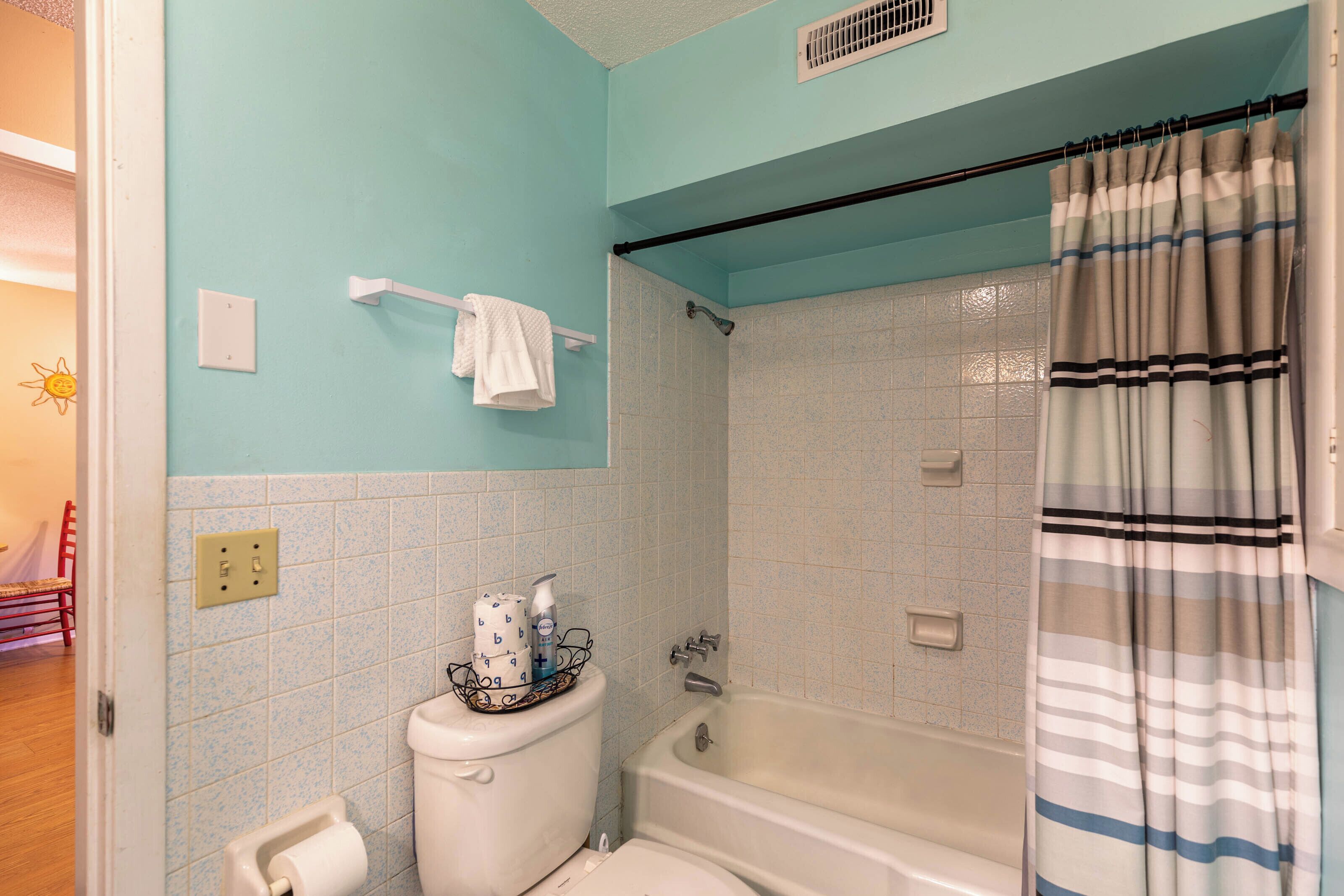 A bathroom with a toilet, a sink, a bathtub, and a shower curtain.