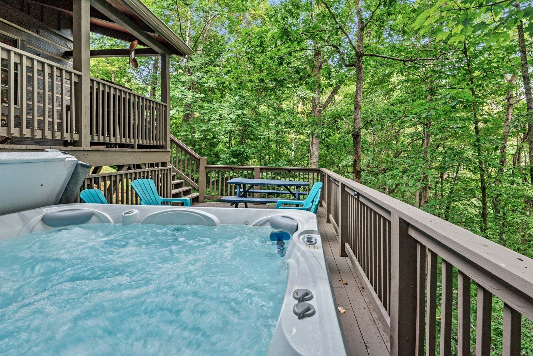 A hot tub on a wooden deck with a view of a forest.