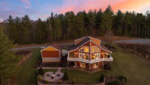 A large two-story house with a wrap-around porch, a separate garage, and a well-maintained lawn. - House Galini (Morganton)