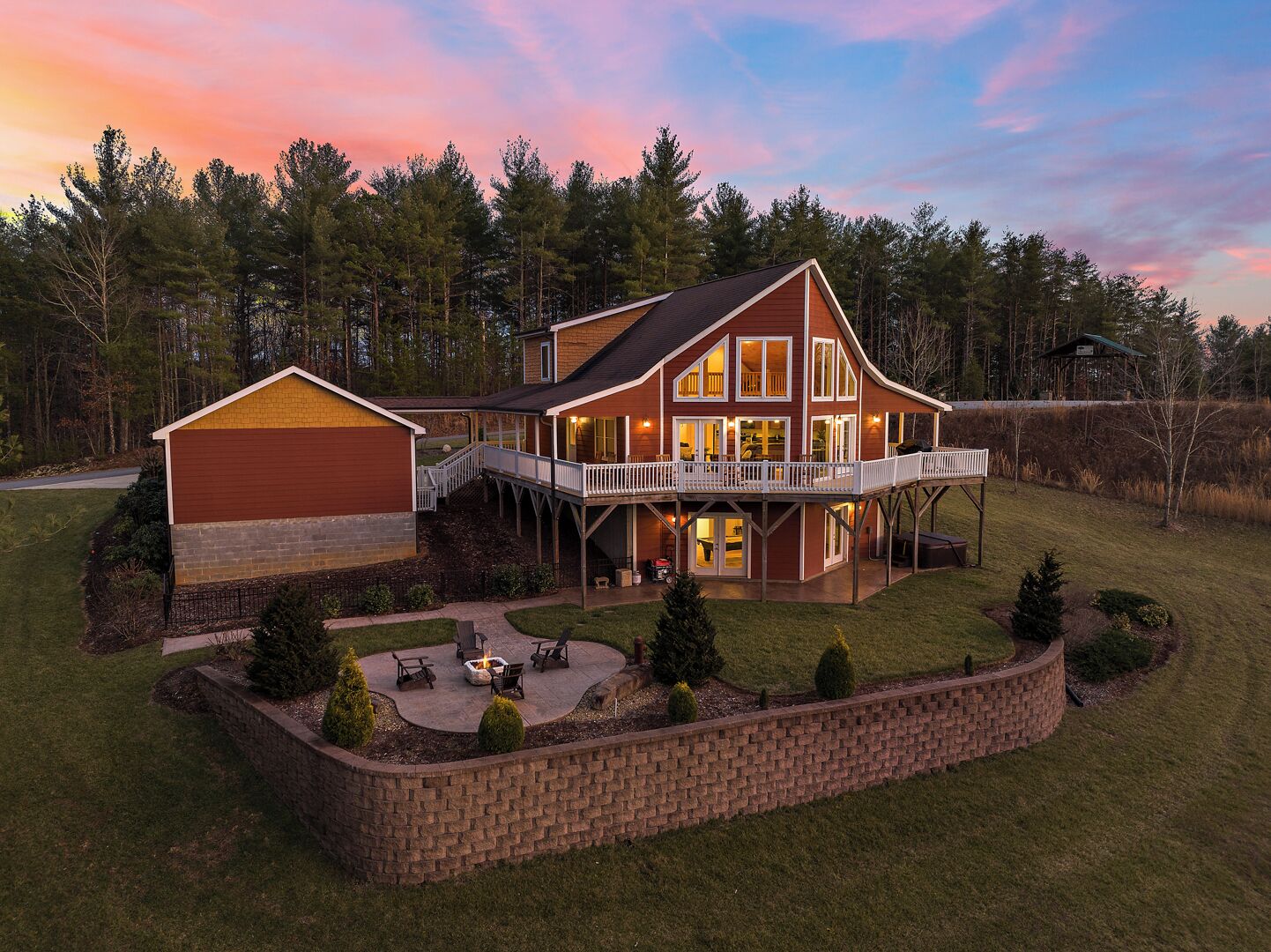 A large two-story house with a covered patio, a deck, and a fire pit area.