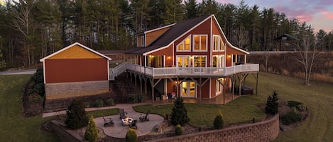 A large two-story house with a covered patio, a deck, and a fire pit area.