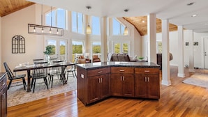 A spacious kitchen with wooden cabinets, a large island, and a dining area with a table and chairs. - House Galini (Morganton)