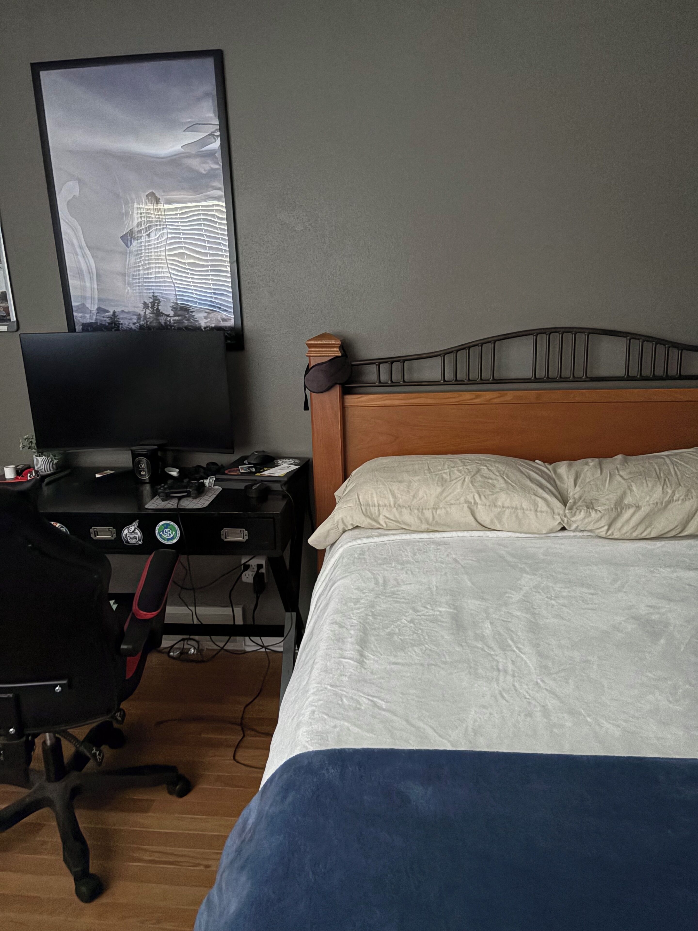 A bedroom with a bed, a desk with a computer, and a wall-mounted TV.