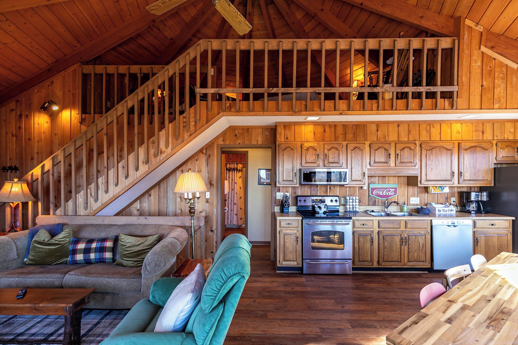 Een ruime woonkamer met een houten trap, een keuken met moderne apparatuur, en een gezellige zithoek.