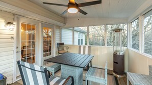 A covered porch with a table and chairs, a ceiling fan, and a heater. - Our Happy Nest (Boone)