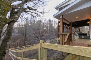 A wooden deck with a metal railing, overlooking a forested area. - Our Happy Nest (Boone)