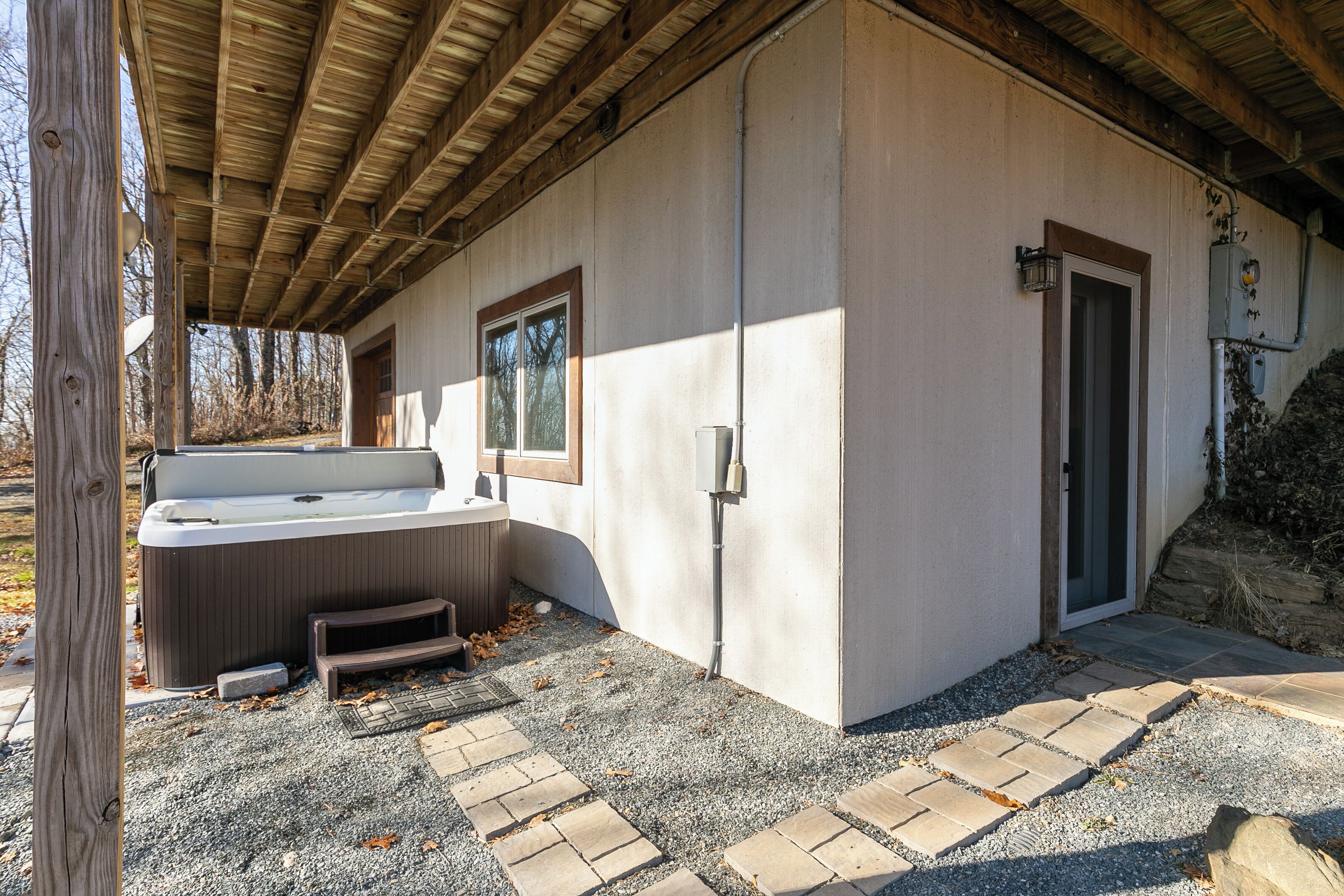 A spa area with a hot tub, a wooden deck, and a covered patio.