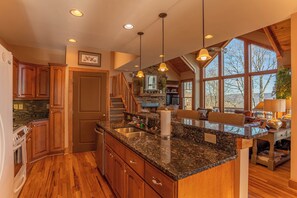 A kitchen with granite countertops, wooden cabinets, and a large island. - B Rock Ridge at Echota - Townhome With Private hot tub (Banner Elk)