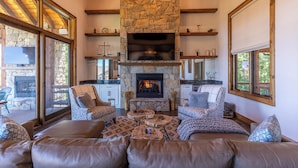 A cozy living room with a stone fireplace, leather sofas, and wooden beams. - Breezeway Lodge at Eagles Nest (Banner Elk)