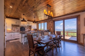 A spacious kitchen with wooden ceiling, large windows, and a dining area with a view of the mountains. - Breezeway Lodge at Eagles Nest (Banner Elk)