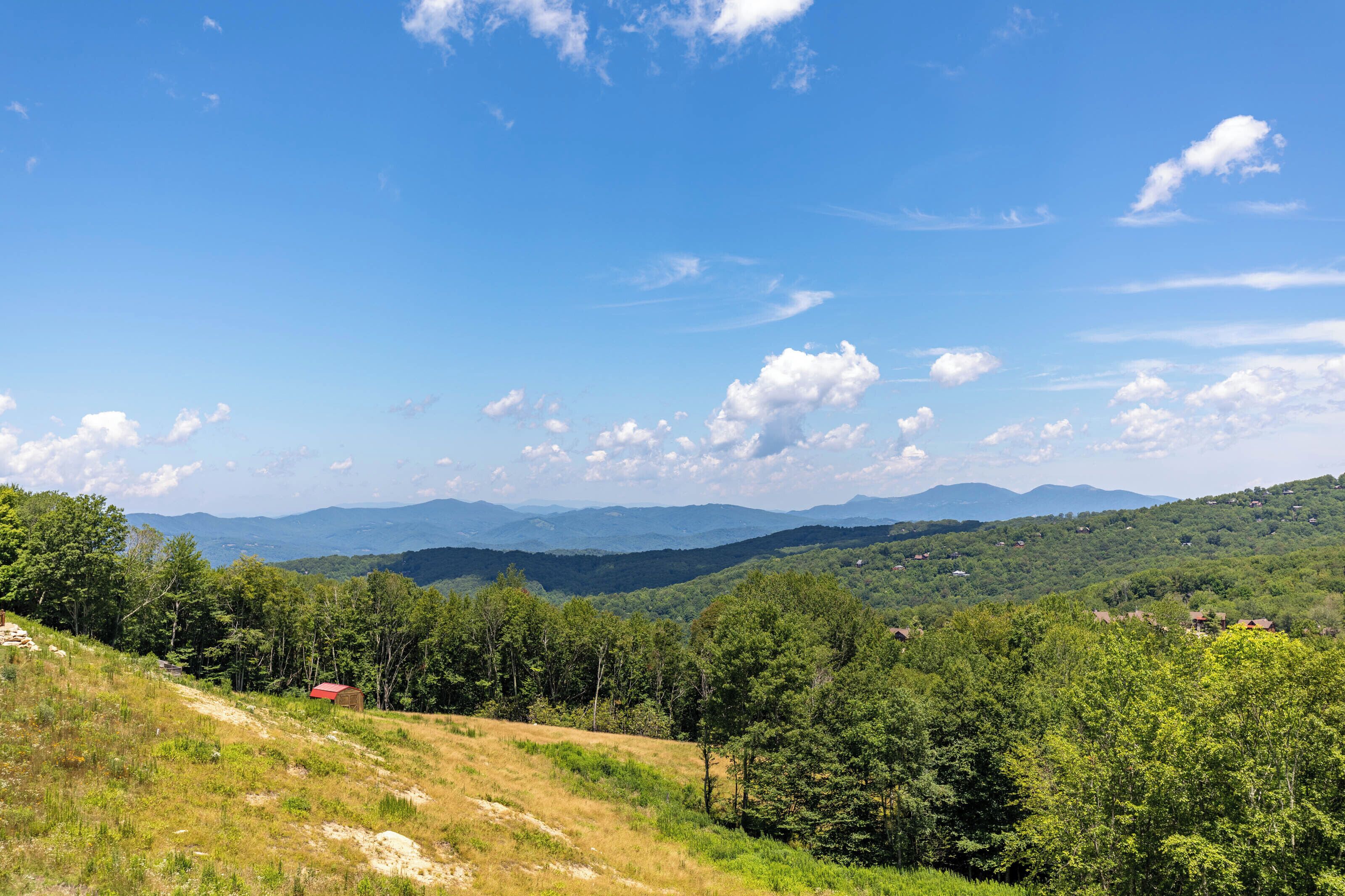 A mountainous landscape with a clear sky and scattered clouds.